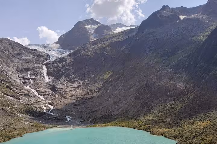 Turquoise Triftsee lake with glacier-fed waterfalls and peaks, scenic stop on Zurich day trip to Trift