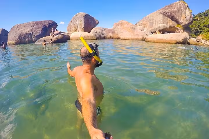 Snorkeler exploring crystal-clear waters and rocky formations on a sunny day at Trinidad beach.