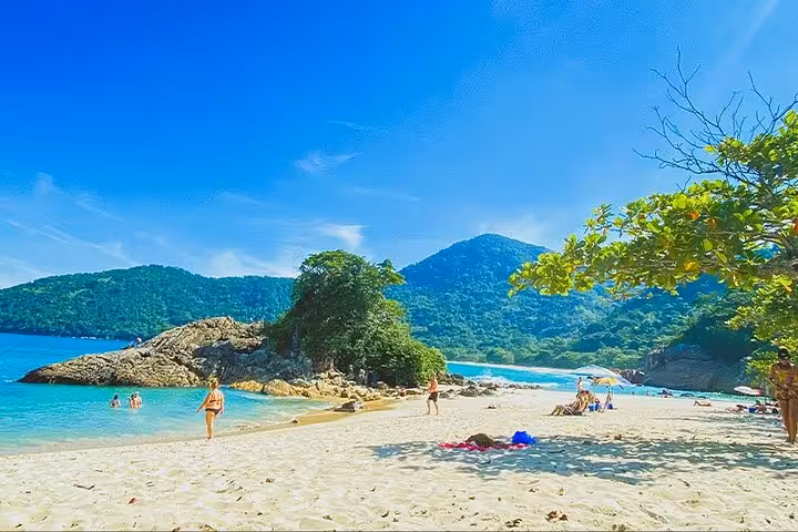Idyllic Trinidad beach scene with clear blue waters, lush greenery, and sunbathers, perfect for a tropical getaway.