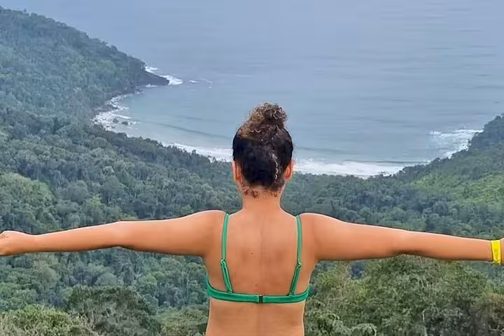 Traveler enjoying panoramic view of Trinidad's lush coastline with the sea in the distance, by Paraty Tours.
