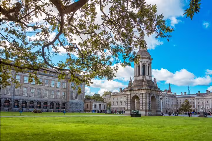 Trinity College Dublin campus with iconic Campanile bell tower, green lawns, and Georgian buildings under blue sky