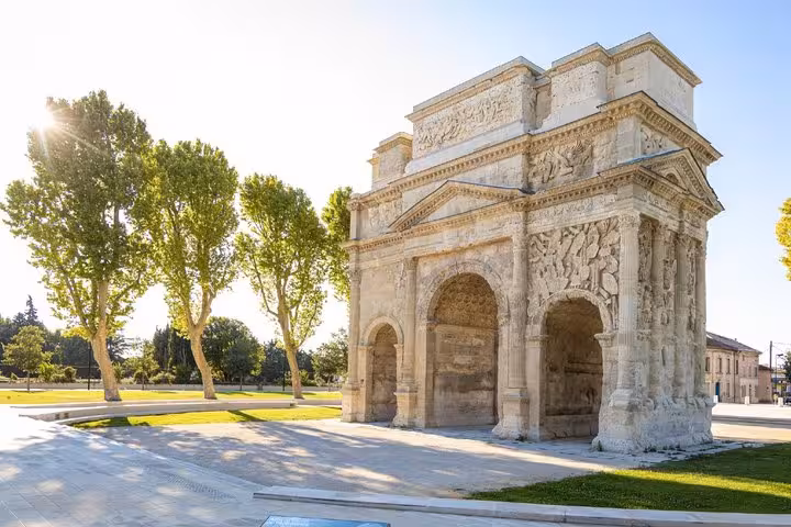 Triumphal Arch of Orange, ancient Roman monument with three arches and carved reliefs, surrounded by trees