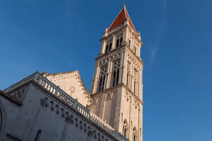 Bell tower of St. Lawrence Cathedral in Trogir, Croatia, with Gothic architecture and red pyramid roof against blue sky