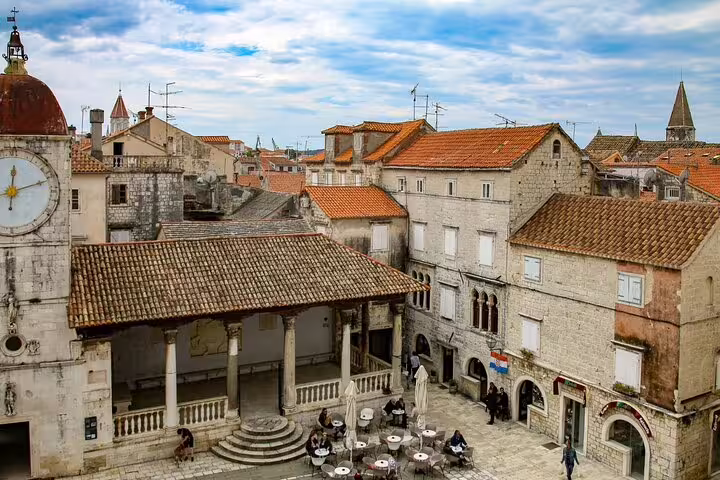 Trogir main square with stone loggia, cafés and historic rooftops, seen on a private guided walking tour