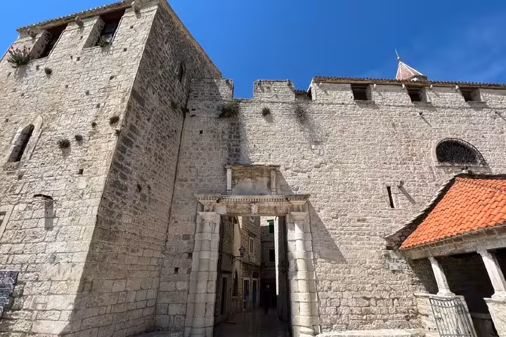 Ancient stone gateway and medieval walls of Trogir old town under blue sky, Croatia