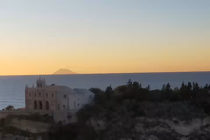 Sunset view of Santa Maria dell’Isola sanctuary in Tropea facing the Tyrrhenian Sea and distant Stromboli volcano in Calabria