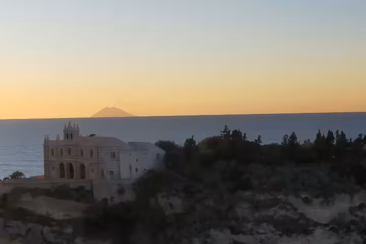 Sunset over Tropea coastline with seaside sanctuary and Stromboli volcano on Calabria nature itinerary from Sila National Park