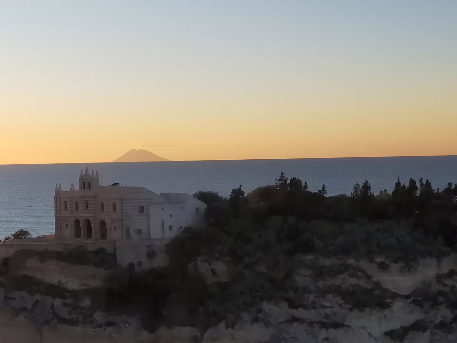 Sunset over Tropea’s Tyrrhenian Sea with clifftop sanctuary and distant Stromboli volcano on guided Calabria tour