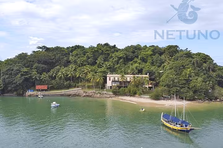 Tropical island with a schooner anchored nearby, providing standup paddle and kayak services for adventure seekers.