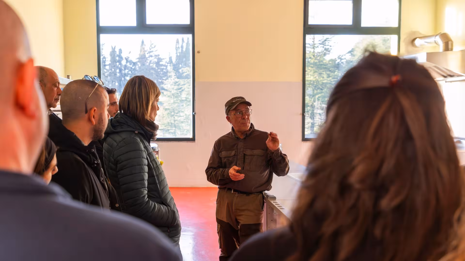 Guide explaining truffle hunting techniques to a group inside a sunlit room in Laconi, Sardinia.