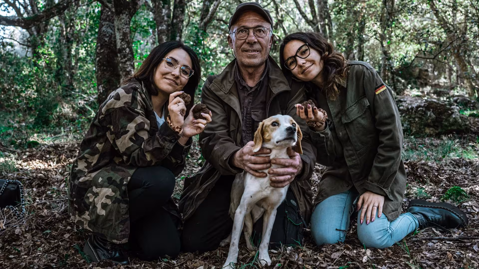 Truffle hunter with participants and dog in Laconi forest, showcasing fresh truffles for a unique culinary adventure.