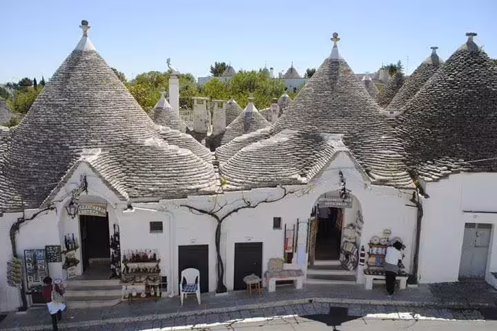 Row of historic trulli houses converted into artisan shops in Alberobello, featured on a private Naples to Puglia day tour