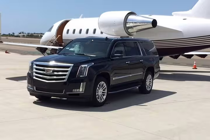Black Cadillac Escalade SUV parked on tarmac beside private jet for Tucson airport transfer
