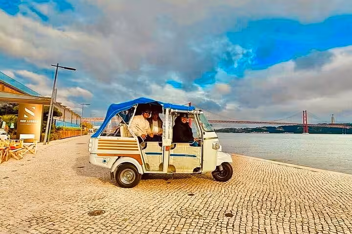 Tuk tuk along Lisbon Belém waterfront near 25 de Abril Bridge on private 2-hour tour with Belém pastries