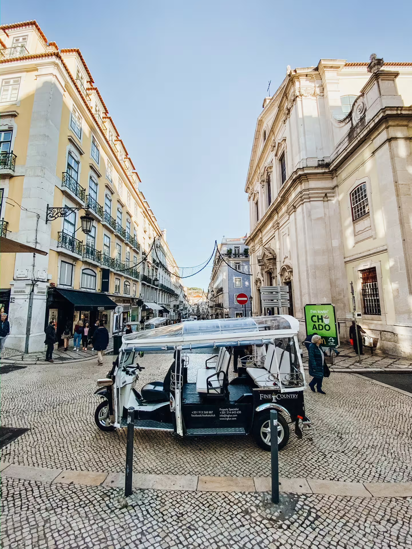 Tuktuk parked on a cobblestone street in Lisbon's historic center, showcasing classic Portuguese architecture.
