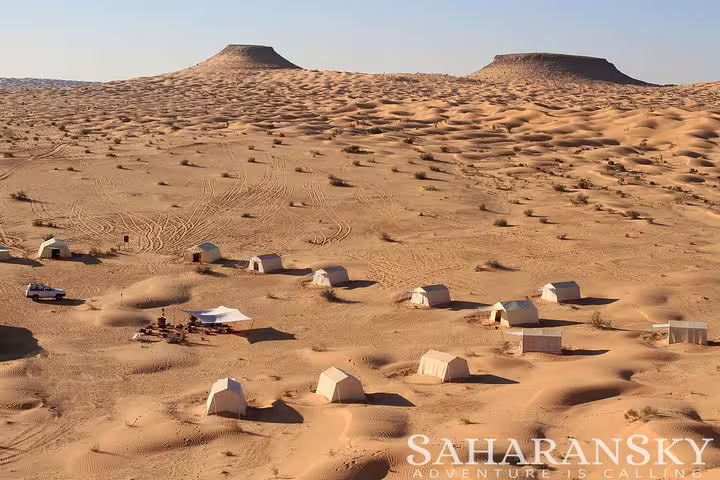 Aerial view of a desert campsite with white tents scattered across the Sahara sands, perfect for a Tunisia buggy safari adventure.