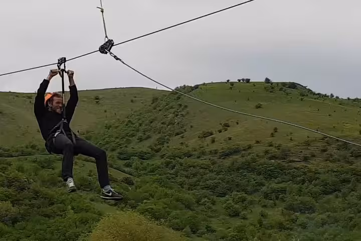 Person zip lining over green hills at Turda Gorge, Romania
