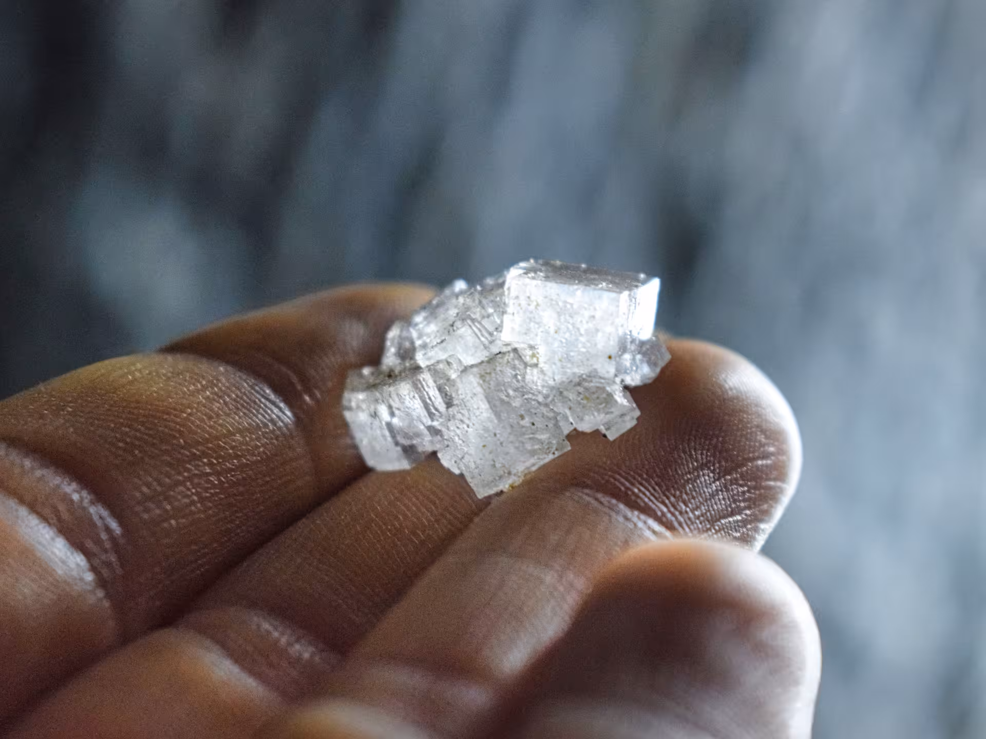 Hand holding a cluster of white halite salt crystals from Turda Salt Mine