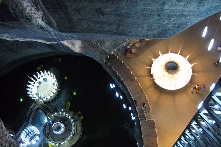 Aerial view of Turda Salt Mine interior with illuminated boat ride platforms and spiral walkways