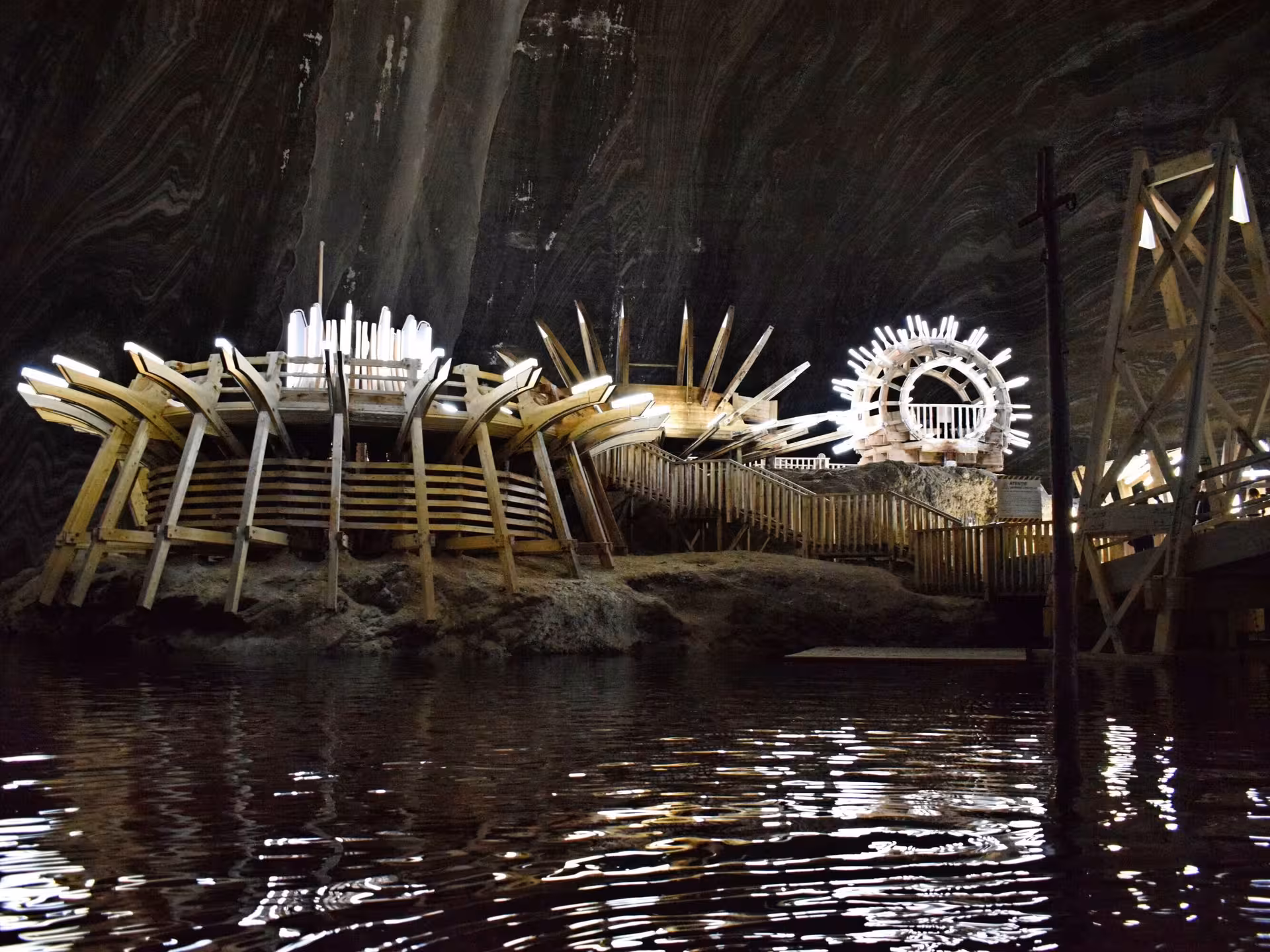 Underground boat ride at Turda Salt Mine with illuminated wooden structures reflected in dark water