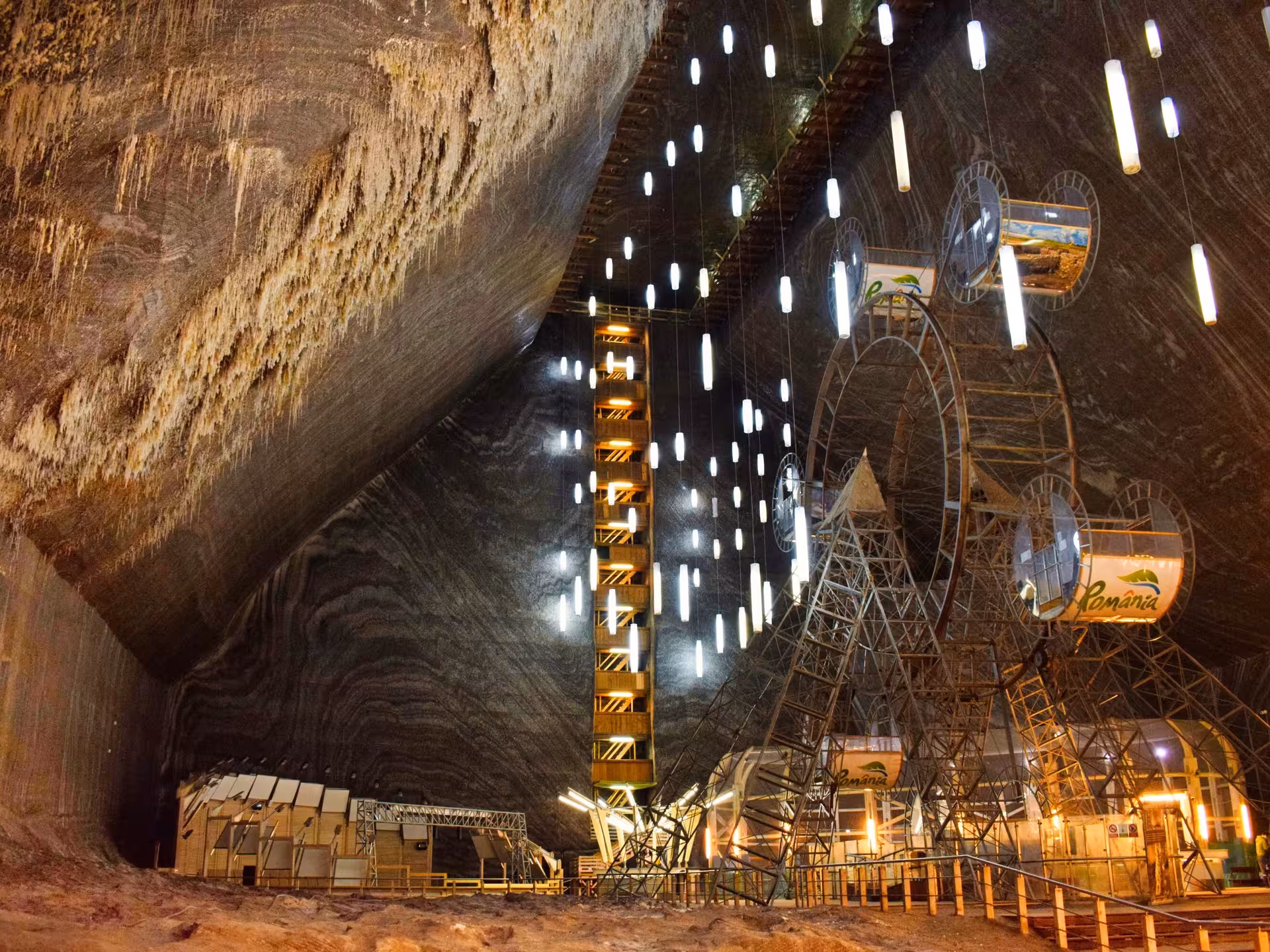Underground Turda Salt Mine cavern with Ferris wheel, hanging lights, and multi-level wooden elevator shaft in Romania
