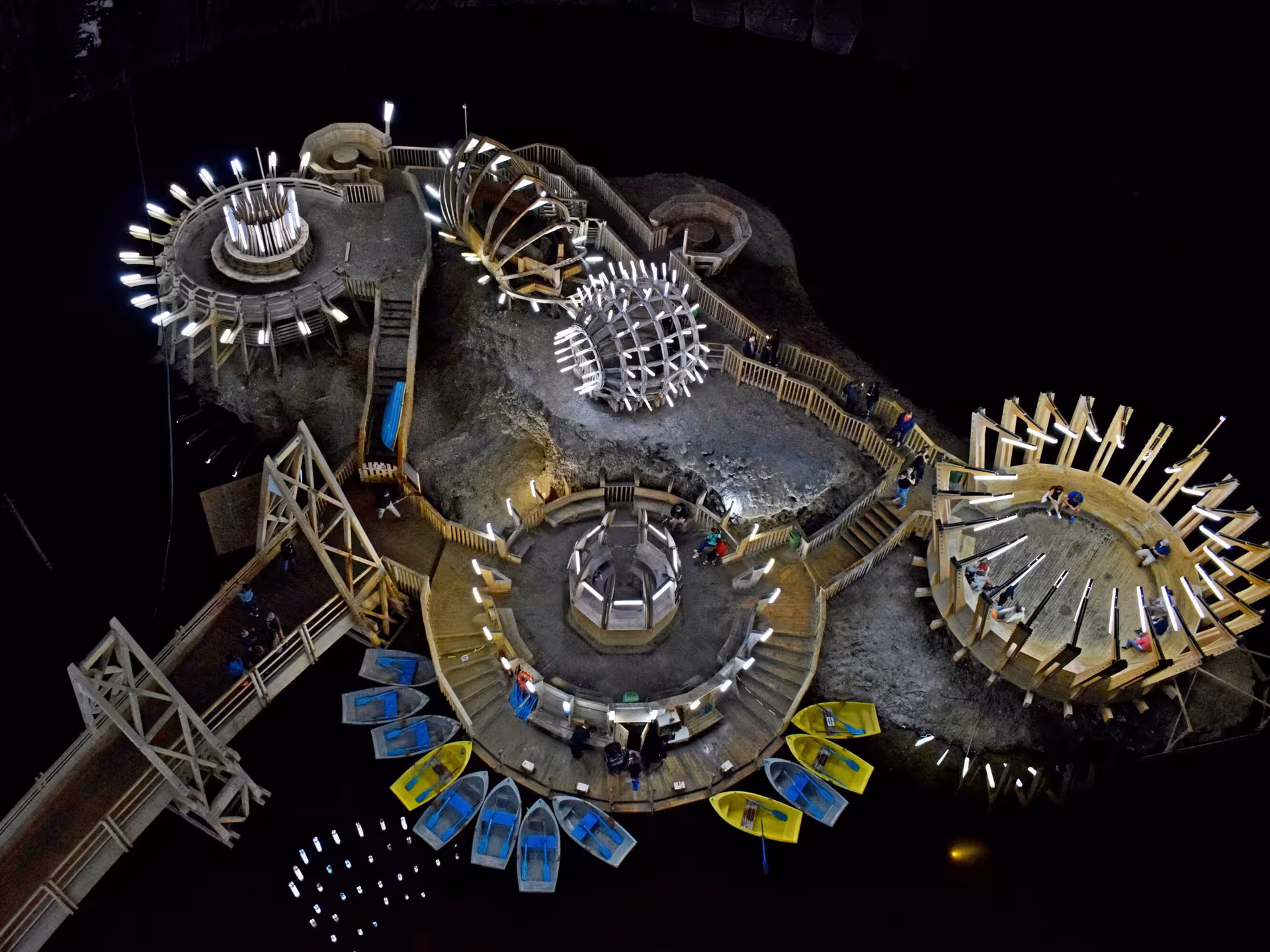 Aerial view of Turda Salt Mine underground island with illuminated wooden structures and colorful rowboats