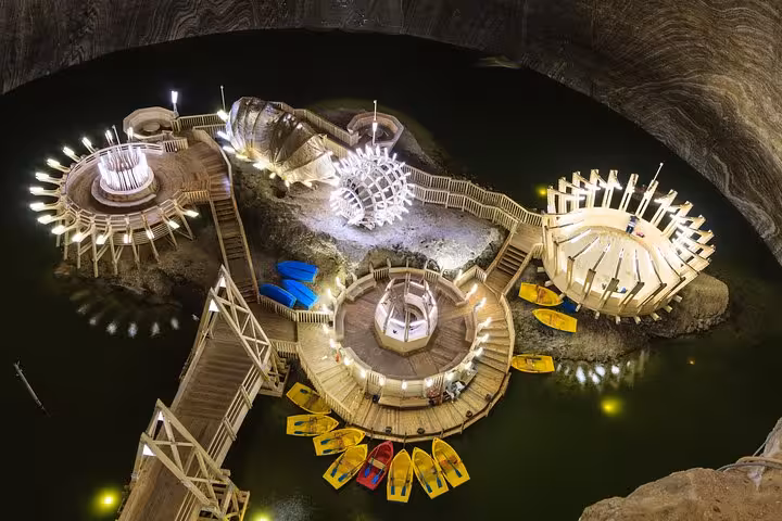 Aerial view of Turda Salt Mine underground lake with wooden platforms, colorful boats, and illuminated attractions