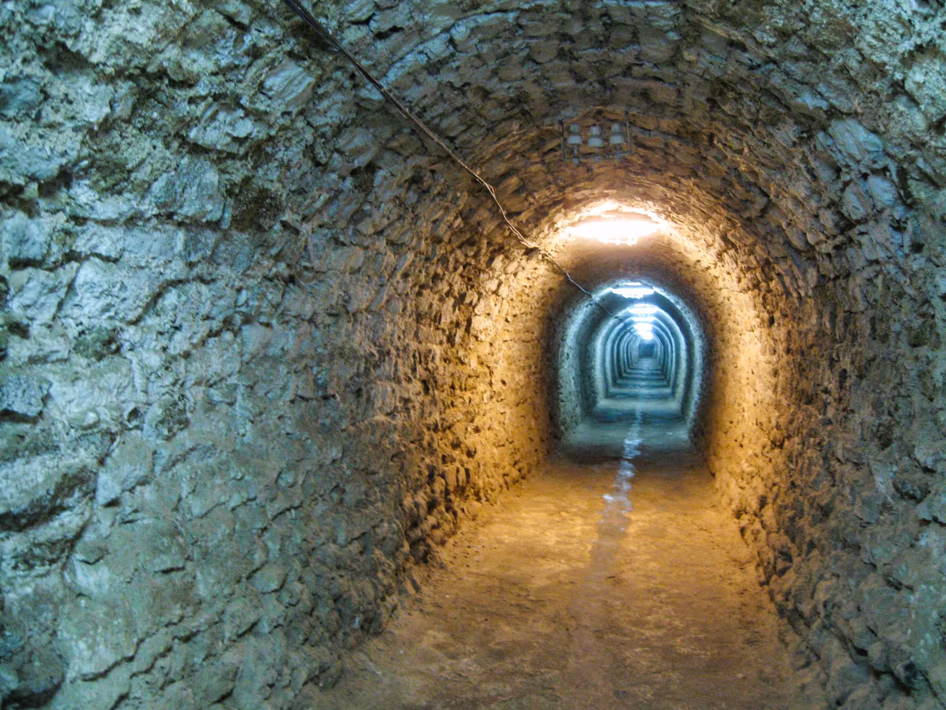 Stone arched tunnel corridor inside Turda Salt Mine illuminated with warm orange lighting