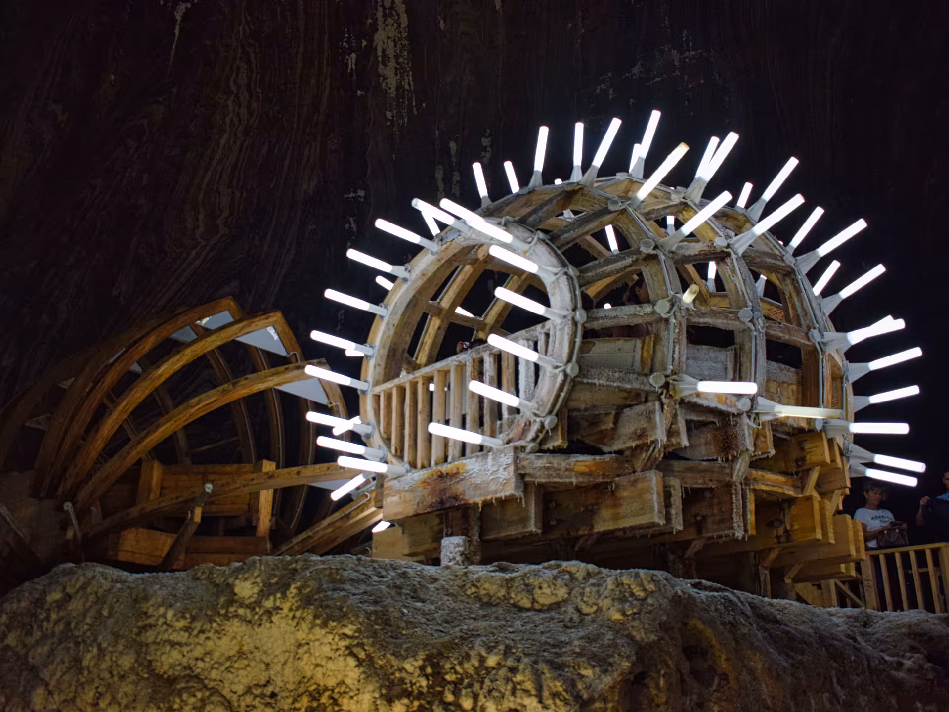 Illuminated historic wooden salt mining wheel inside Turda Salt Mine on a guided day trip from Cluj Romania