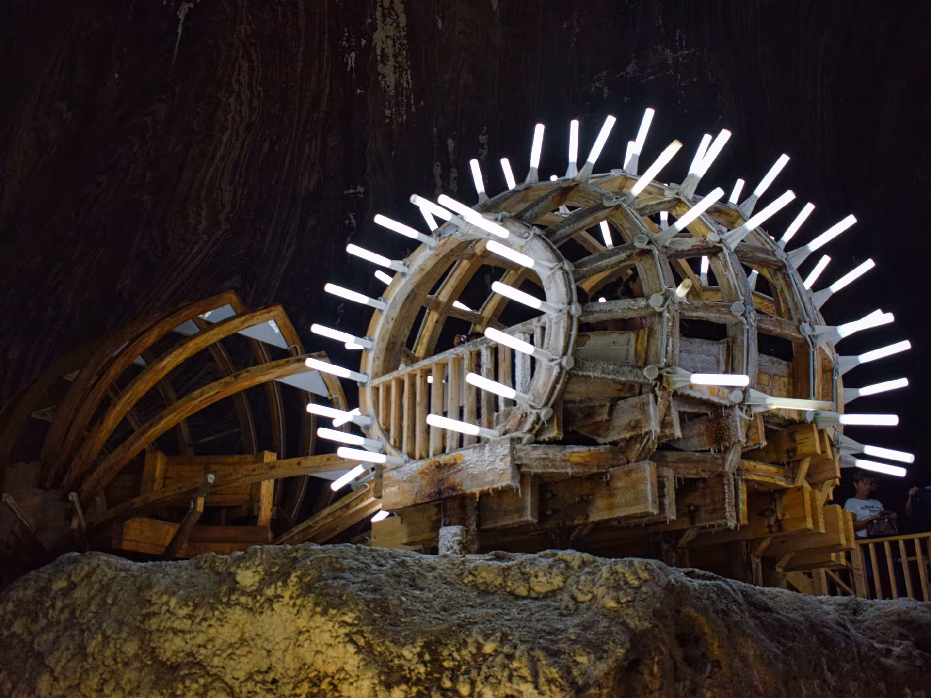 Illuminated ancient wooden salt wheel inside Turda Salt Mine on a guided tour from Cluj Romania