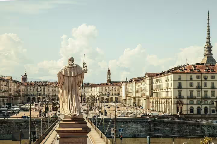 White statue overlooking Piazza Vittorio Veneto in Turin with Mole Antonelliana in background