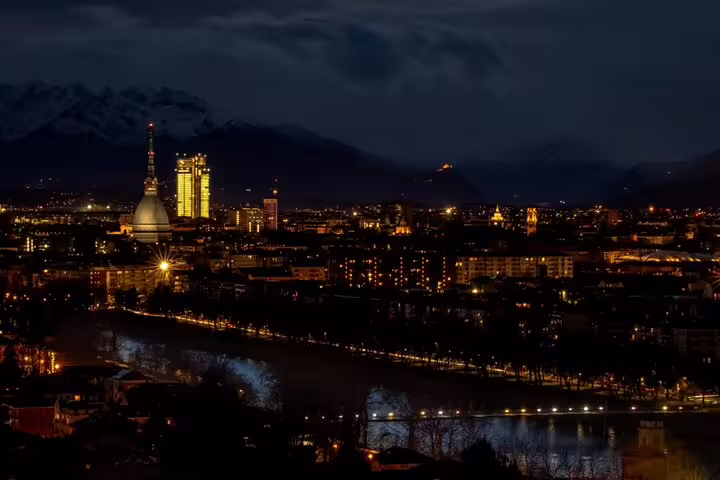 Turin city skyline at night with Mole Antonelliana illuminated and Alps in background