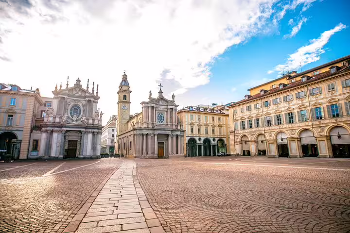 Wide cobbled Piazza San Carlo in Turin with twin baroque churches and clock tower visited on a top sights walking tour