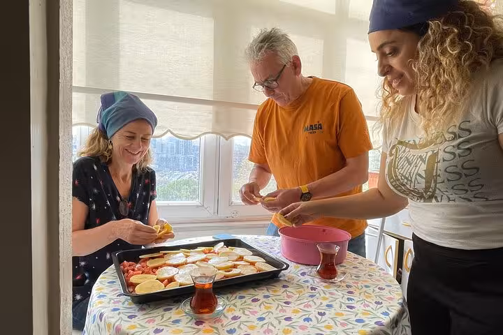 Travelers prepare a Turkish tray bake and sip tea during an authentic Istanbul home cooking class with locals