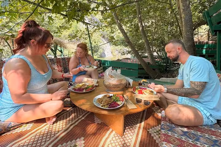 Group enjoying authentic Turkish cuisine at a rustic outdoor setting in a tranquil village environment, perfect for food lovers.