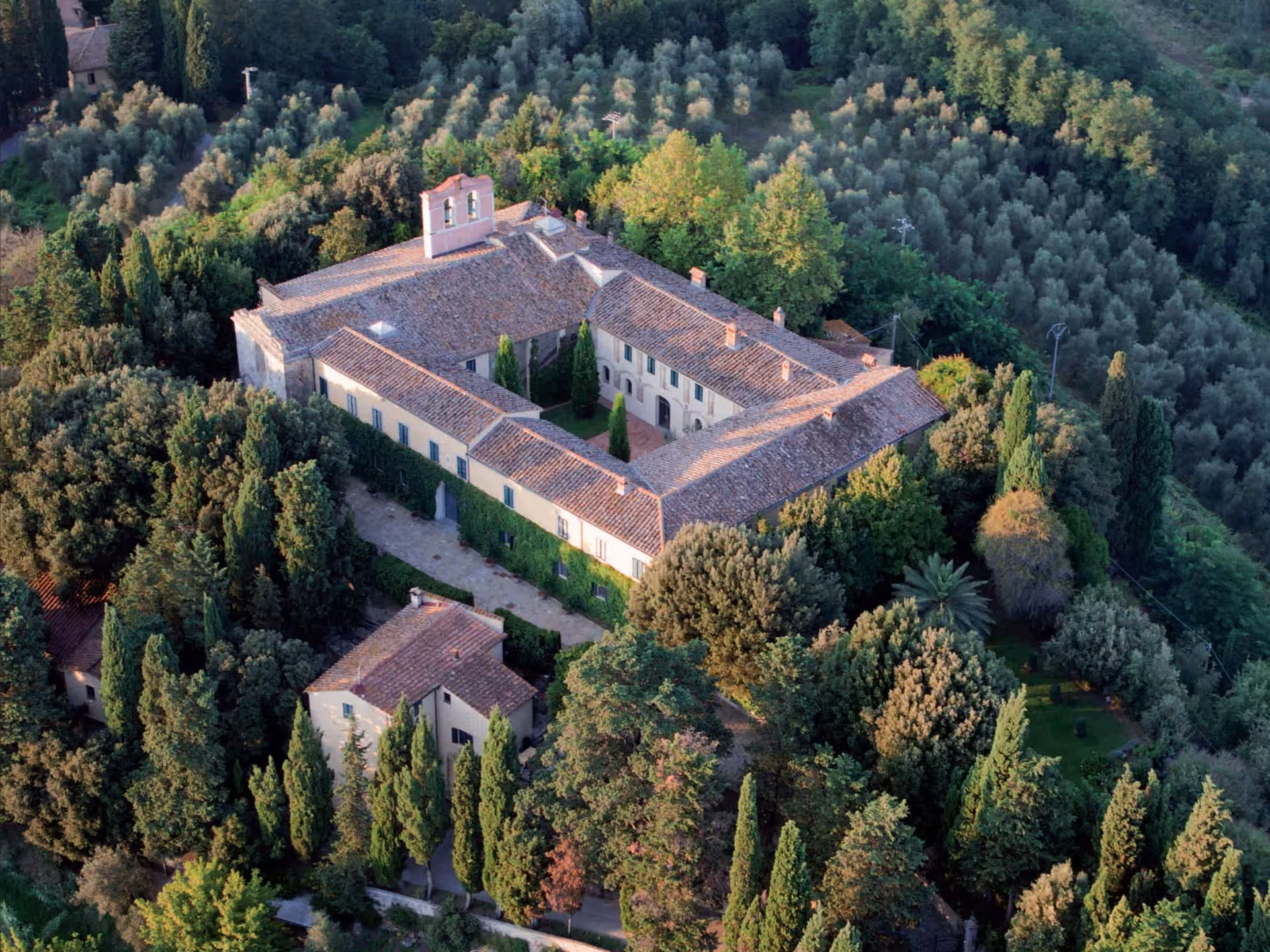 Aerial view of a historic Tuscan abbey surrounded by lush greenery, part of the Abbey Tour near Pisa.