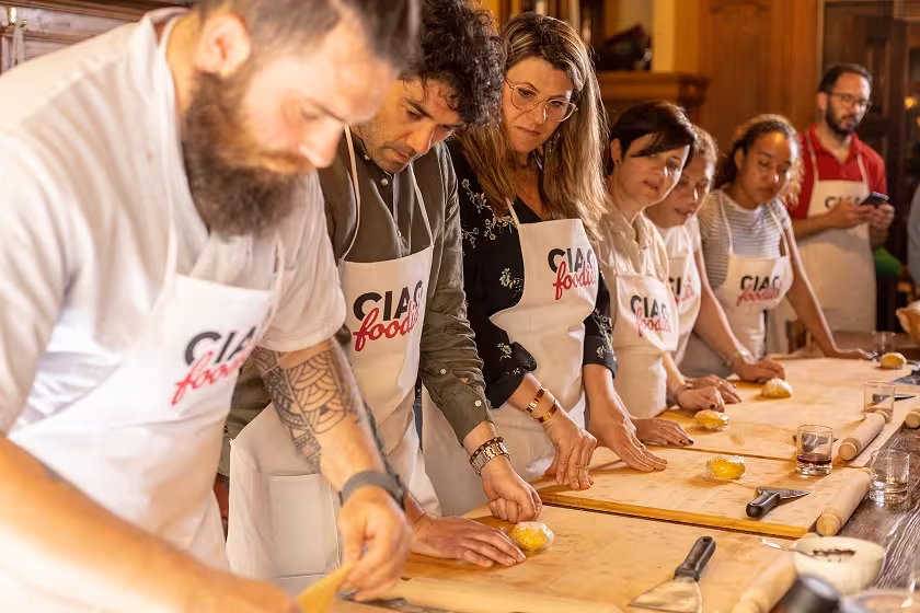 Participants in a Tuscan cooking class in Florence knead dough, showcasing hands-on culinary skills in a small group setting.