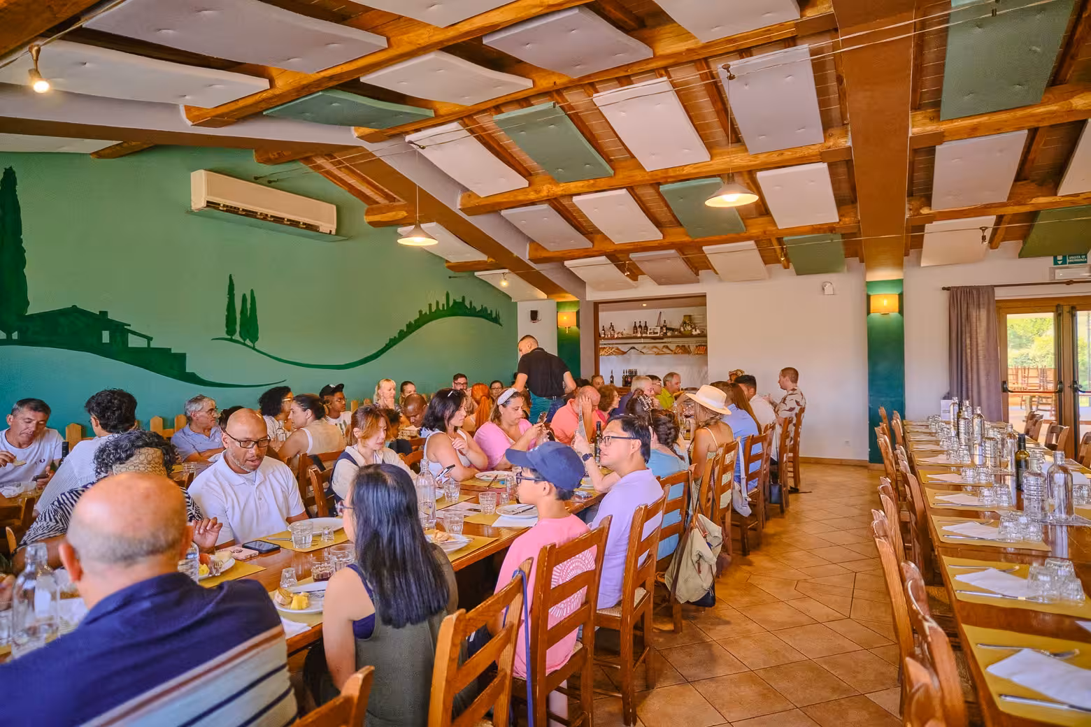 Group of tourists enjoying a communal dining experience in a cozy Tuscan restaurant with rustic decor.