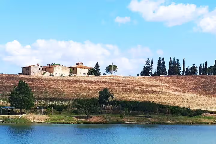 Traditional Tuscan farmhouse on a golden hillside above a tranquil lake, visited on private Chianti countryside wine tours