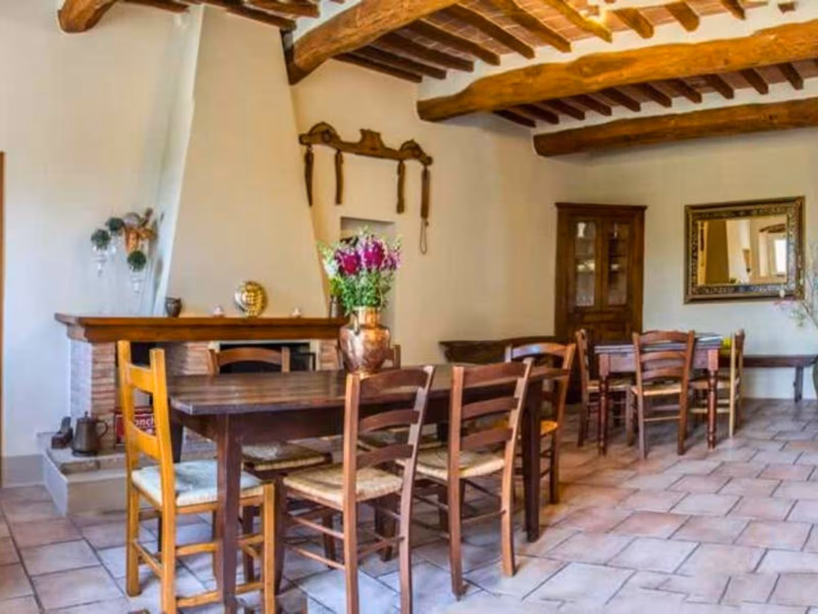 Rustic Tuscan farmhouse dining room with wooden beams and cozy fireplace for culinary experiences.