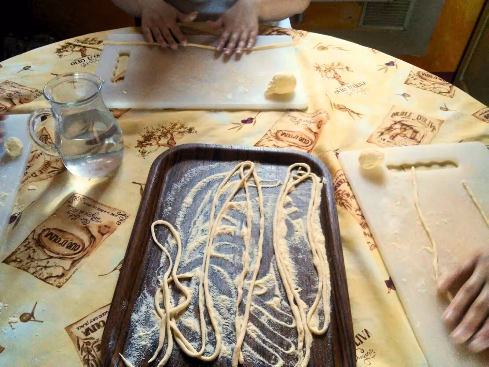 Hands crafting fresh pasta on a floured board at a Tuscany farmhouse cooking class, showcasing authentic Italian culinary skills.