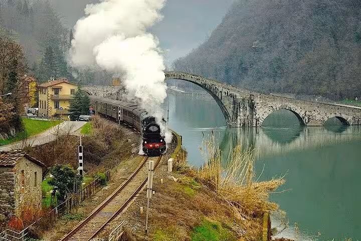 Scenic train journey through Tuscan countryside with views of Devil's Bridge near Lucca.