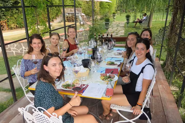 A small group enjoys wine tasting and a delicious meal in a picturesque Tuscan garden setting.
