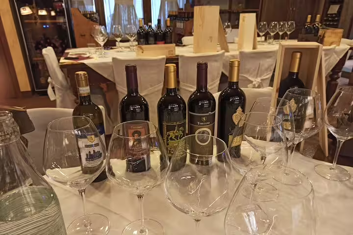 Elegant Tuscan wine tasting setup with premium bottles and glasses on a farm lunch table near Pisa and Lucca, Italy
