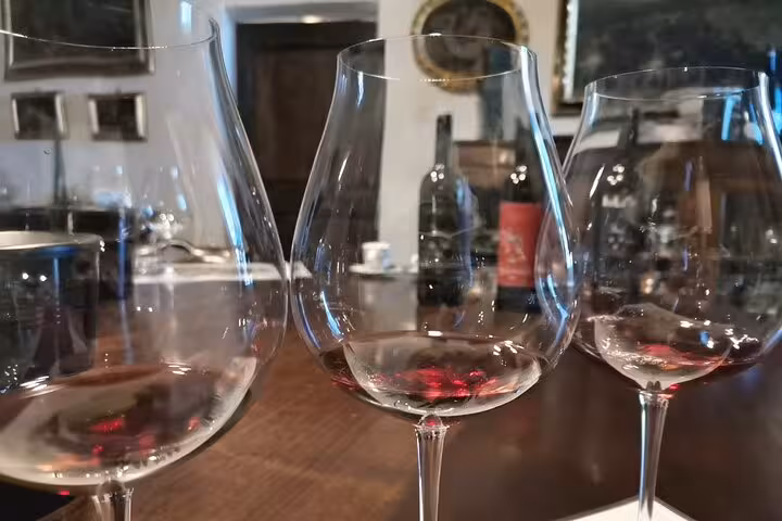 Close-up of three wine glasses with red wine on a rustic table in a Tuscan cooking class setting near Rome.