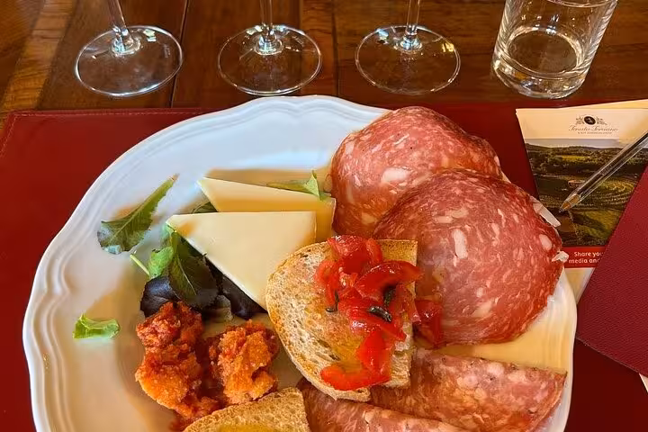 Italian antipasto platter with cured meats, cheese, and bruschetta, part of Tuscany Vespa tour lunch experience.