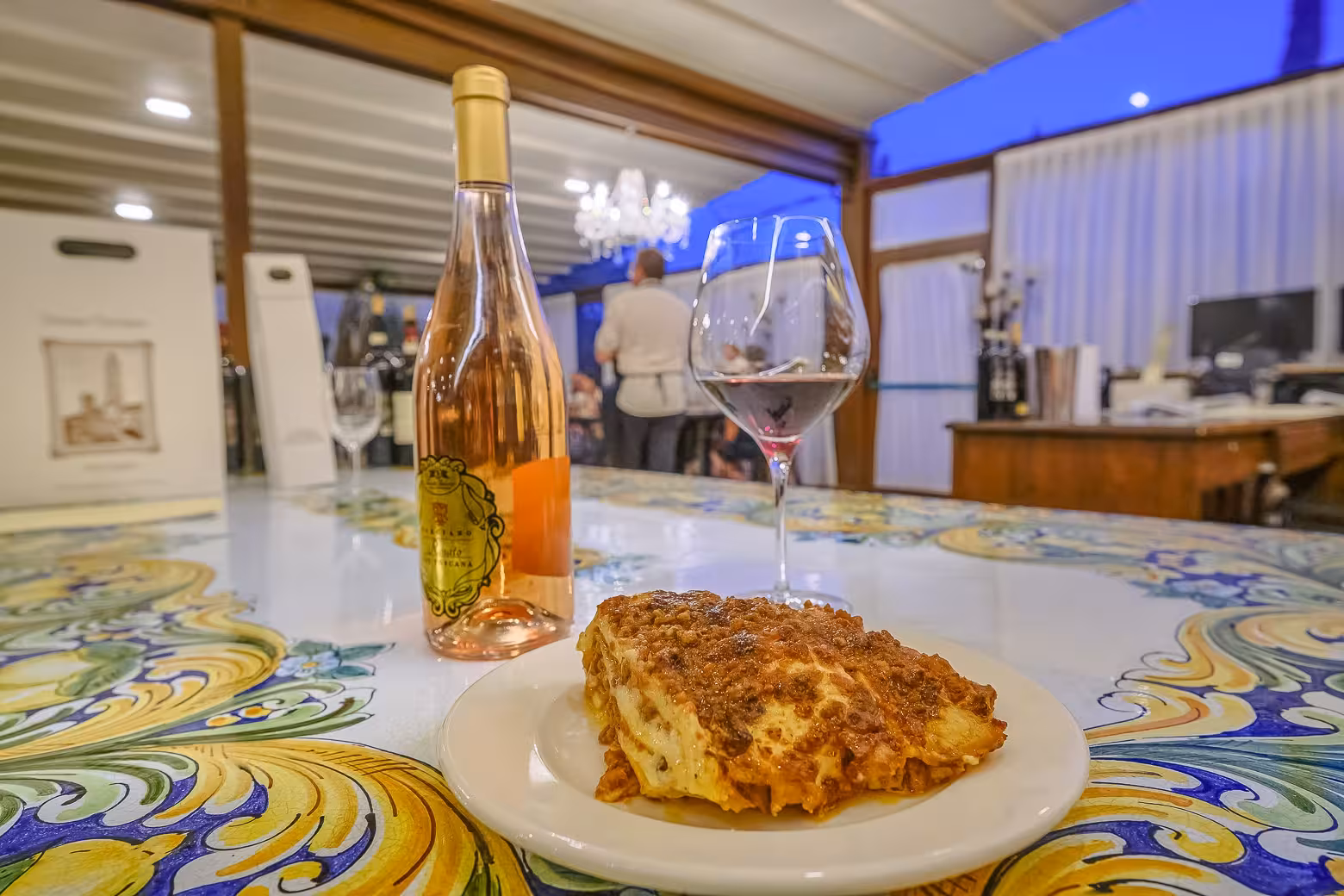 Lasagna and Tuscan wine bottle on a decorative table during Tuscany by Vespa tour from Florence.