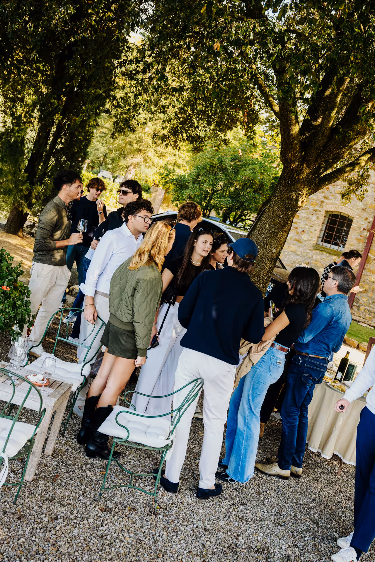 Group of guests socializing outdoors at a Tuscan wine tasting event under shaded trees