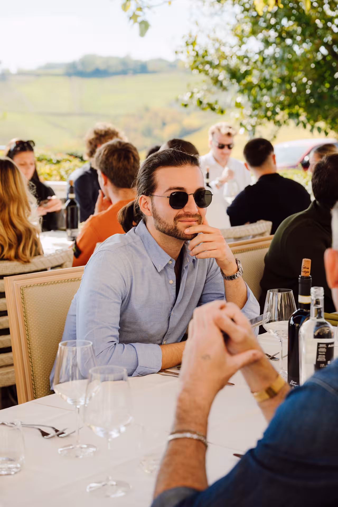 Man in sunglasses enjoying outdoor wine tasting lunch at a Tuscan vineyard terrace
