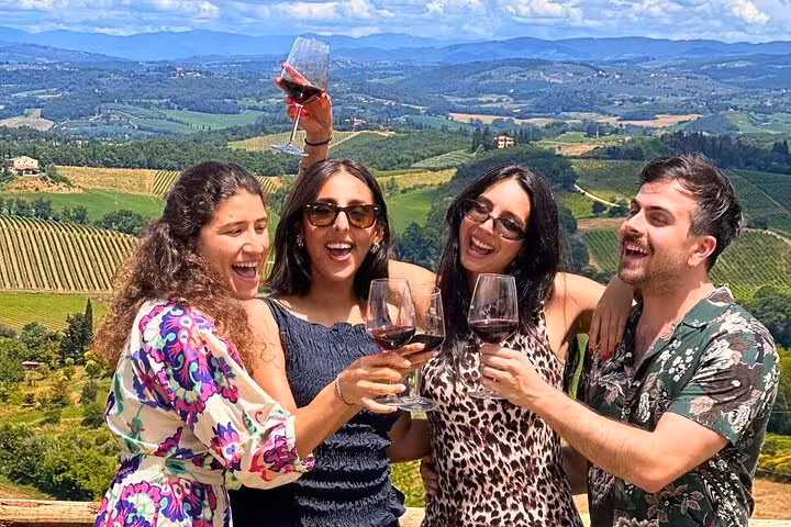 Group of friends enjoying wine with panoramic views of Tuscan vineyards during the Tuscany Wine Tour from Rome.